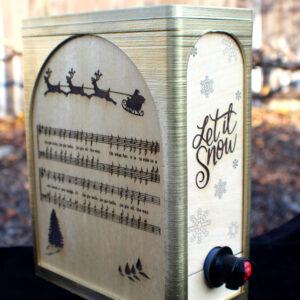 An engraved oak box for bag-in-a-box wine. The rectangle box has an end spout, a gold frame, and oak panels engraved with holiday messages and images.